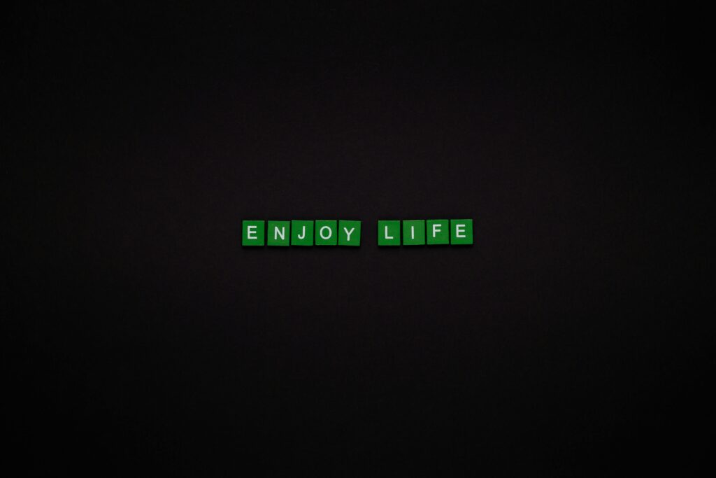 Green letter tiles spelling 'ENJOY LIFE' on a black background, perfect for motivational content.